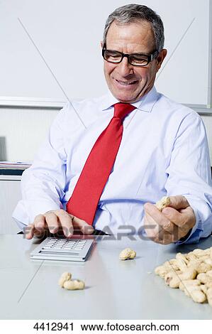 Stock Image - Businessman with peanut and calculator . Fotosearch