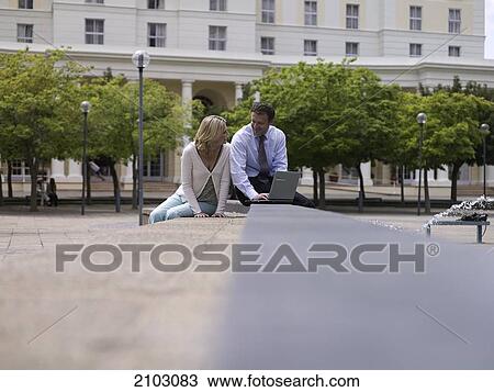 Businesswoman and businessman sitting near fountain with laptop View Large Photo Image Stock Image - Businesswoman and businessman sitting near fountain with laptop . Fotosearch