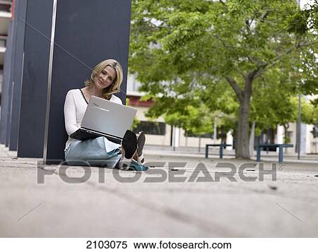 Businesswoman sitting at roadside and using laptop View Large Photo Image Stock Photography - Businesswoman sitting at roadside and using laptop . Fotosearch