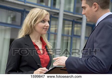 Stock Photo - Businesswoman taking dictation from businessman . Fotosearch