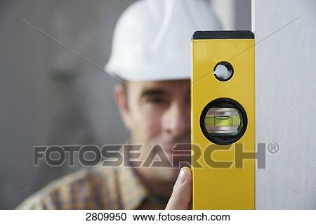 Stock Image - Carpenter holding spirit level . Fotosearch