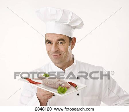 Stock Image - Chef holding dish of fish . Fotosearch