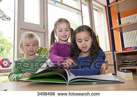 Stock Photo - Children looking at picture book, low angle view . Fotosearch