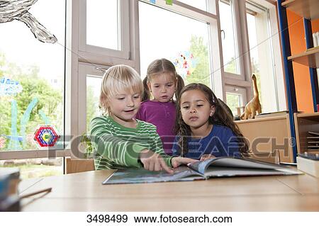 Stock Photo - Children looking at picture book, low angle view . Fotosearch
