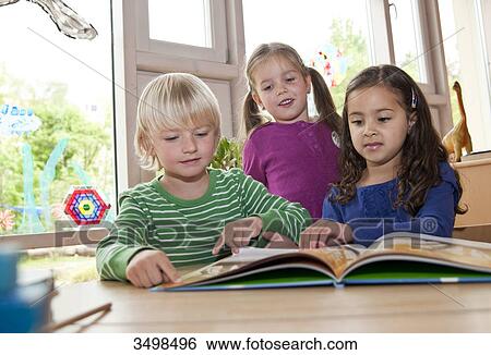 Stock Photograph - Children looking at picture book, low angle view . Fotosearch