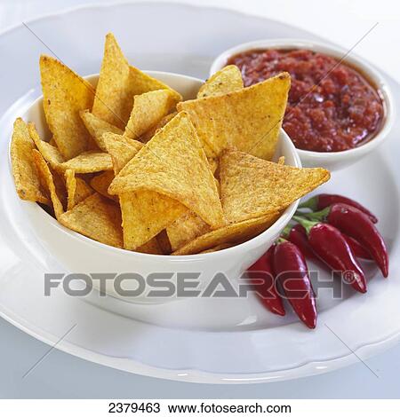 Stock Image - Close-up of bowl of chips with red chili peppers and sauce on plate . Fotosearch