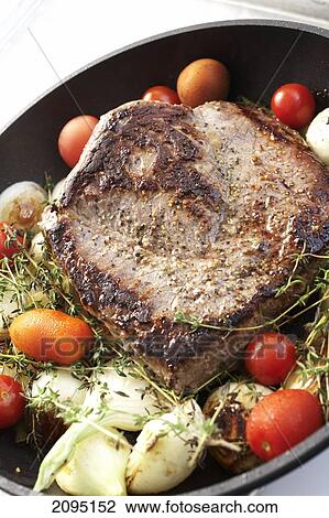 Stock Image - Close-up of fried meat with tomatoes in pan . Fotosearch
