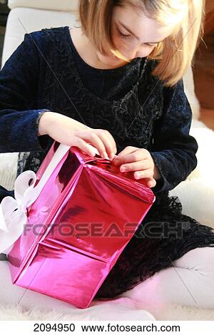 Stock Image - Close-up of girl unwrapping gift box . Fotosearch