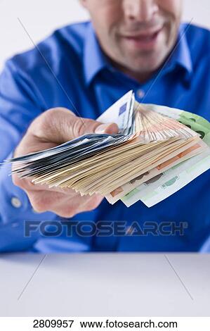 Stock Photo - Close-up of man giving Euro bills . Fotosearch
