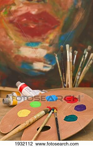 Stock Image - Close-up of paint tray with paintbrushes and tubes on table . Fotosearch