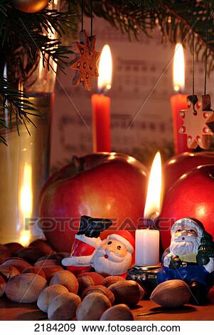 Stock Photo - Close-up of Santa Claus figurines with walnuts and burning candles . Fotosearch