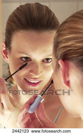 Stock Image - Close-up of woman applying mascara and smiling . Fotosearch