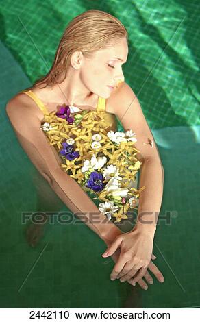 Stock Image - Close-up of young woman in swimming pool with flowers . Fotosearch