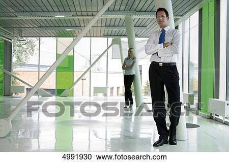 Stock Image - Confident businessman with woman in background . Fotosearch