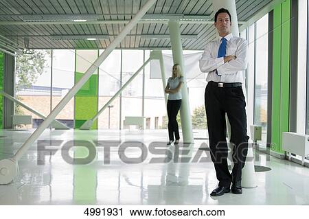 Confident businessman with woman in background View Large Photo Image Stock Image - Confident businessman with woman in background . Fotosearch