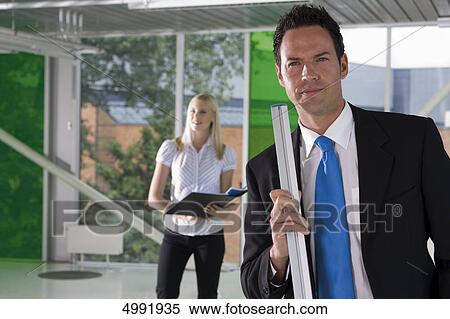 Confident businessman with woman in background View Large Photo Image Stock Photography - Confident businessman with woman in background . Fotosearch