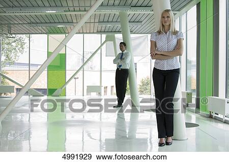 Confident businesswoman with man in background View Large Photo Image Stock Photo - Confident businesswoman with man in background . Fotosearch