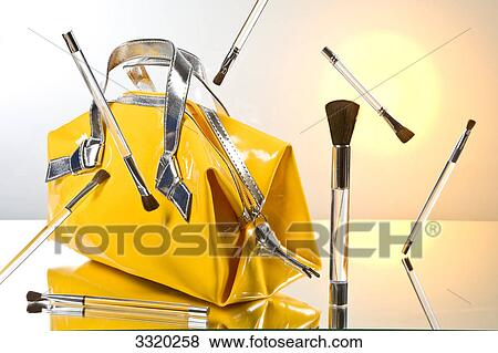 Cosmetic brushes hovering around a hand bag View Large Photo Image Stock Photo - Cosmetic brushes hovering around a hand bag . Fotosearch