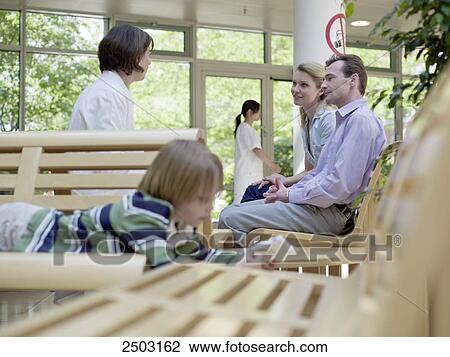 Stock Image - Couple consulting with female doctor at waiting area . Fotosearch