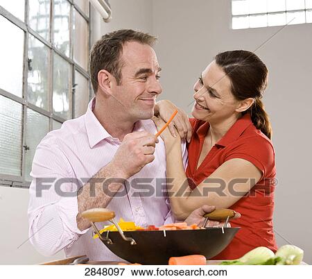 Stock Photo - Couple cooking food and romancing . Fotosearch