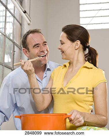 Stock Photo - Couple cooking food and romancing . Fotosearch