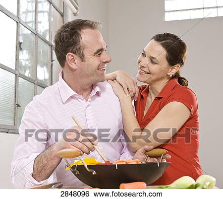 Stock Photograph - Couple cooking food and romancing . Fotosearch