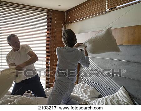 Couple having pillow fight on bed View Large Photo Image Stock Photo - Couple having pillow fight on bed . Fotosearch