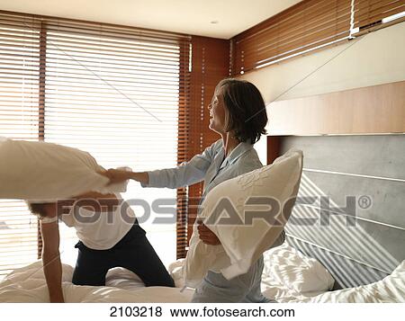 Couple having pillow fight on bed View Large Photo Image Stock Photo - Couple having pillow fight on bed . Fotosearch