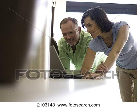 Stock Photo - Couple looking at laptop and smiling . Fotosearch