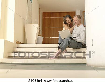 Picture - Couple looking at laptop on steps . Fotosearch