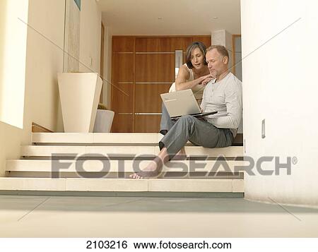 Couple looking at laptop on steps View Large Photo Image Stock Photograph - Couple looking at laptop on steps . Fotosearch