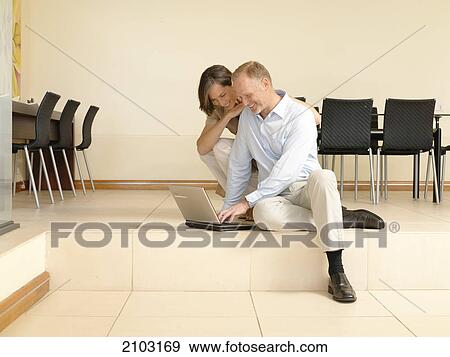 Couple looking at laptop View Large Photo Image Stock Photo - Couple looking at laptop . Fotosearch