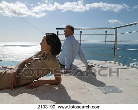 Stock Image - Couple resting at poolside . Fotosearch