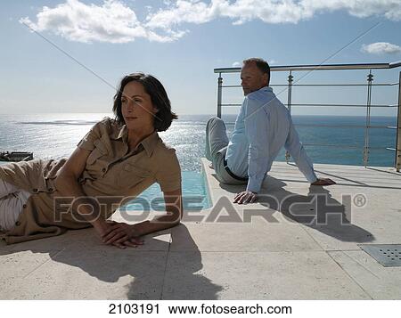 Stock Image - Couple resting at poolside . Fotosearch