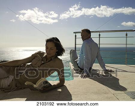 Stock Image - Couple resting at poolside . Fotosearch