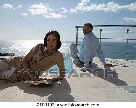 Couple resting at poolside View Large Photo Image Stock Image - Couple resting at poolside . Fotosearch