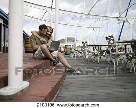 Couple using laptop at harbor View Large Photo Image Stock Photograph - Couple using laptop at harbor . Fotosearch