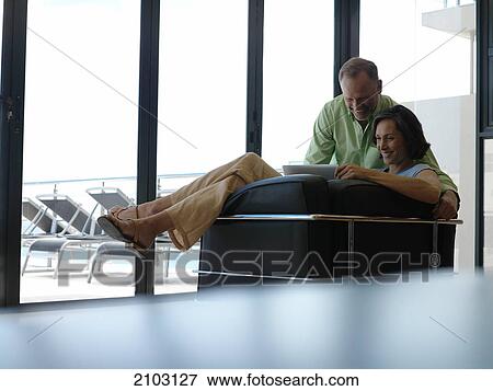 Couple using laptop on couch View Large Photo Image Stock Photo - Couple using laptop on couch . Fotosearch