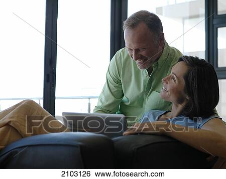 Stock Photograph - Couple using laptop on couch . Fotosearch