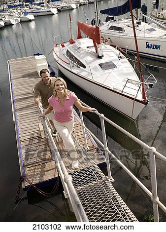Stock Image - Couple walking on platform at harbor . Fotosearch