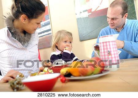 Stock Photography - Couple with their daughter at dining table . Fotosearch