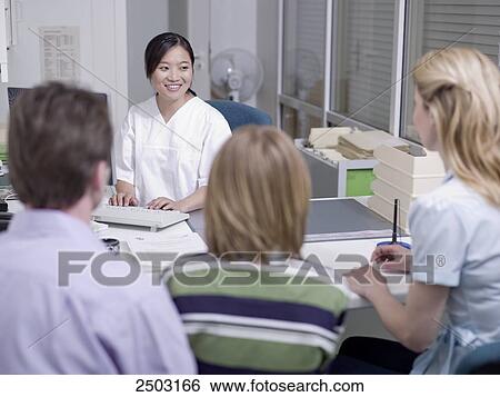 Stock Photograph - Couple with their son discussing with female doctor . Fotosearch