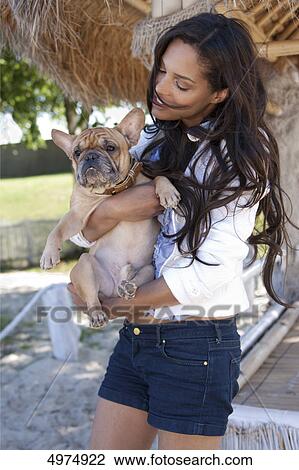 Stock Image - Dark-haired woman holding pug . Fotosearch