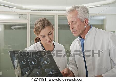 Stock Image - Doctor and doctor's assistant with x-ray talking . Fotosearch