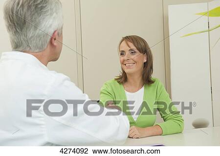 Stock Image - Doctor and female patient shaking hands . Fotosearch