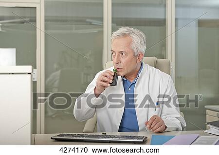 Doctor at desk drinking liquor secretly View Large Photo Image Stock Image - Doctor at desk drinking liquor secretly . Fotosearch