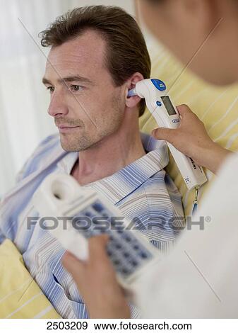 Stock Photo - Doctor examining male patient's ear . Fotosearch
