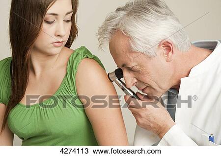 Stock Image - Doctor examining patient's arm . Fotosearch