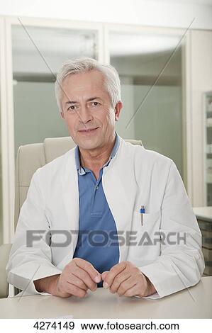 Doctor sitting behind desk View Large Photo Image Stock Photo - Doctor sitting behind desk . Fotosearch