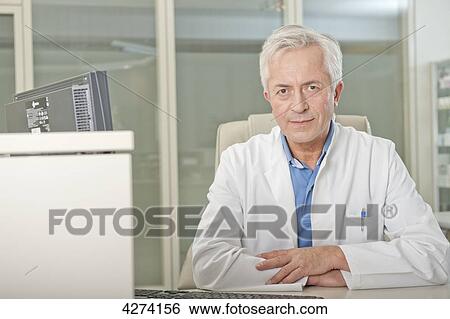 Stock Photograph - Doctor sitting behind desk . Fotosearch